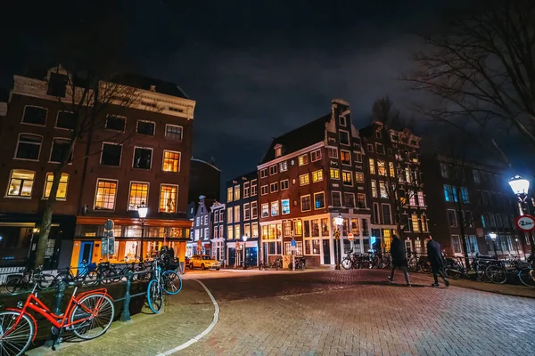 Amsterdam, Niederlande - März 2020: Nachtansicht der Brücke über den Wasserkanal in der historischen Innenstadt mit typischen Tanzhäusern — Stockfoto