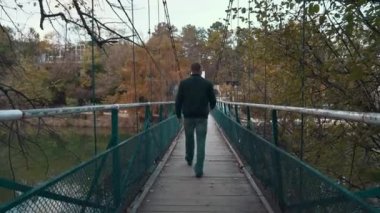Nehir üzerindeki eski asma köprü ve adam gri sonbahar gününde gider. Melankoli, depresyon ya da yalnızlık