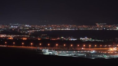 Gece körfezli aydınlık Gelendzhik şehrinin görüntüsü, deniz koyunun suyuna yansıyor.