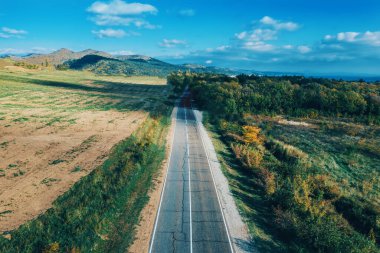 Boş asfalt yolu ya da güzergah, ya da dağ yamaçlarında yeşil çayırlar ve ormanlar arasında özgürlük ve seyahat fikri