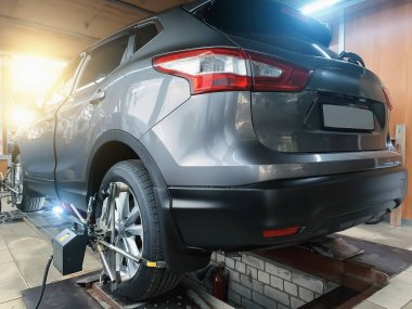 Araba serviste. Algılayıcılar SUV tekerleklerinde hizalama camber ayak parmağını kontrol ediyor. Arabanın şasisi ve süspansiyonuyla çalış