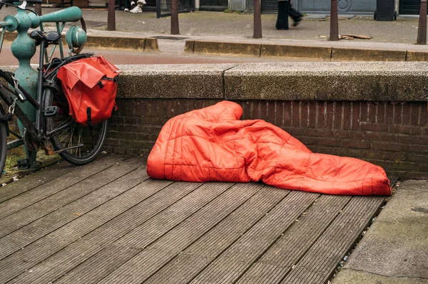 Pria tunawisma tidur di bawah selimut merah di pusat kota Eropa — Stok Foto