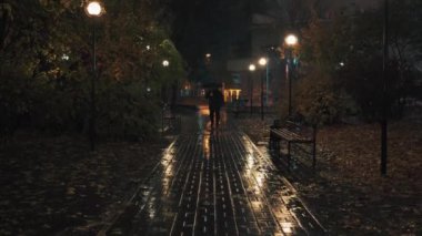 Yağmurlu sonbahar gecelerinde ve akşamları şemsiyeyle gezen bir adam.