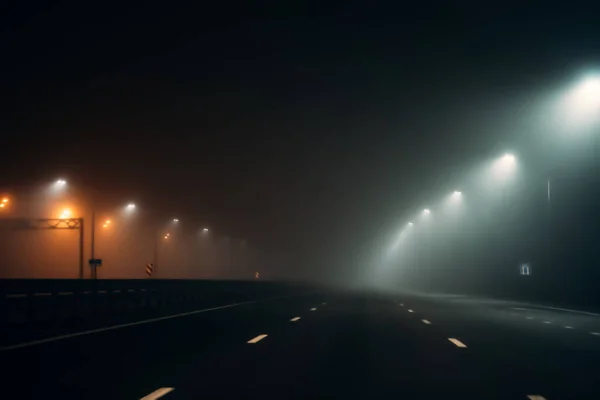 Empty illuminated by city lamps foggy road at night in misty weather