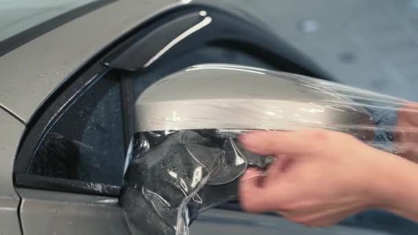 Робочі руки обмотують вологою плівкою захисту від фарби або покриттям проти грі на дзеркалі автомобіля. Деталізація автомобіля — стокове відео