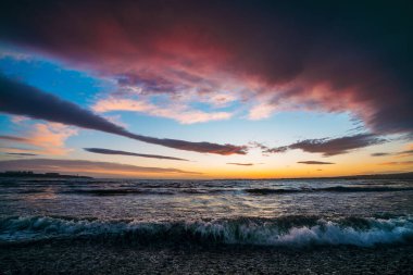 Denizde dramatik gün batımı. Okyanusun üzerinde kırmızı ve mavi renkli güzel bulutlar gün batımı su yüzeyi