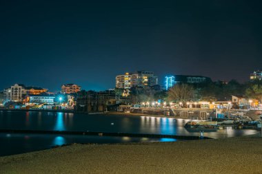 Geceleyin Gelendzhik tatil köyü sahil şeridi, arka planda modern binalar.