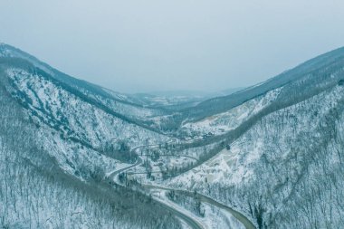 Kışın karlı havada dağ zirveleri arasındaki dağ geçidinde İHA 'dan hava manzarası