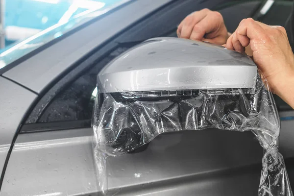 Установка PPF на боковое зеркало автомобиля. Защитная пленка - защитное полиуретановое покрытие для лакокрасочных работ на автомобиле — стоковое фото