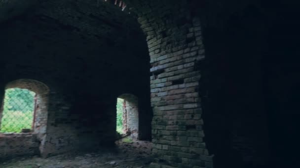 Μέσα σε παλιό τούβλο σκοτεινό εγκαταλελειμμένο ναό ή φρούριο με τοξωτά θησαυροφυλάκια, ανατριχιαστικό παρωχημένο αρχαίο κτίριο — Αρχείο Βίντεο