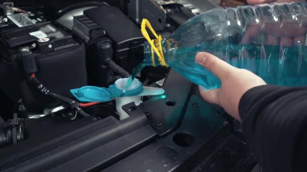 Wlewanie niebieskiej, płynnej szyby z plastikowej butelki do samochodu, zbliżenie. Płyn do mycia szyb samochodowych — Wideo stockowe