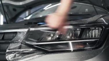 Detaylı çalışanlar, plazma veya boya koruma filmlerini araba farında çalışan aletlerle düzeltiyorlar. Polimer koruyucu dış kaplama, kapat