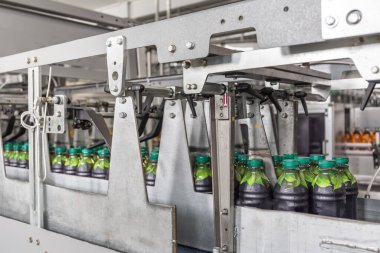 İçecek fabrikasında meyve suyu bulunan plastik şişeler modern otomatik taşıma hattı veya şerit