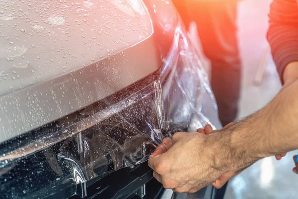 Película de protección del coche o proceso de PPF de envolver e instalar en la capucha del coche por las manos del trabajador detailer, primer plano —  Fotos de Stock