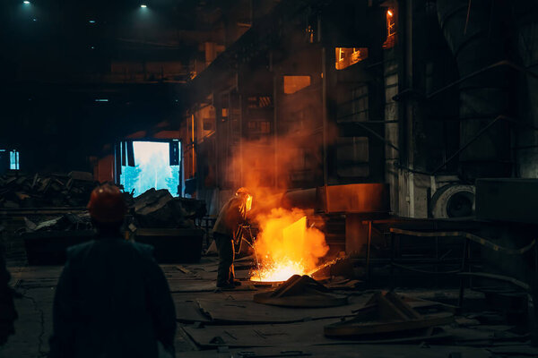 Worker in blast furnace factory interior. Metal casting process in metallurgical plant