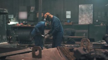 Maskeli işçiler, metalürji dökümhanesinde çalışıyor.