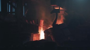 Çelik atölye fırınında küfe kıvılcımlar saçan parlak sıvı demir ya da metal dökülüyor