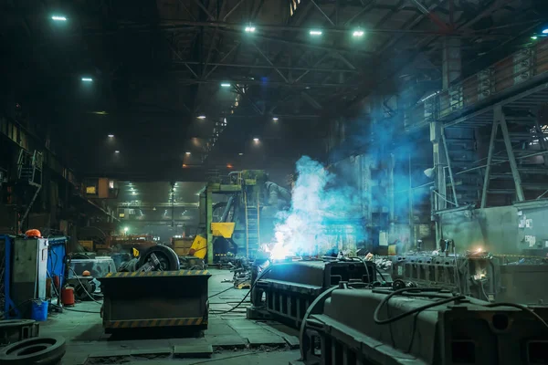Saldatore del metallo che lavora con la saldatrice ad arco all'interno della fabbrica metallurgica della fonderia. Lavorazione dei metalli — Foto Stock