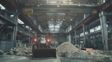 Fabrikadaki büyük sanayi atölyesinde kovalı traktör veya kazıcı, ağır sanayi konsepti