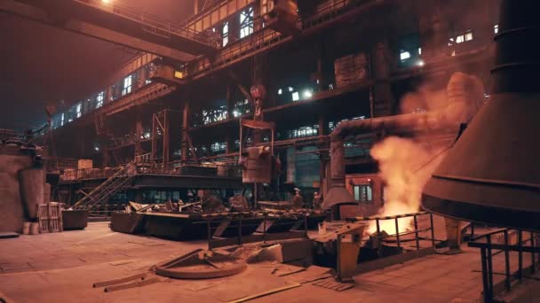Gieterij interieur. Blast oven met vuur en rook en bewegende emmer container met gesmolten ijzer door bundel kraan. Industrie voor zware metallurgie — Stockvideo