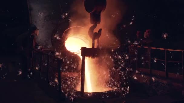 Proceso de fundición de hierro en fábrica de fundición. Metal fundido brillante con chispas que se vierten desde el alto horno hasta el contenedor, trabajadores en máscaras y proceso de control de desgaste protector. Industria metalúrgica pesada — Vídeos de Stock