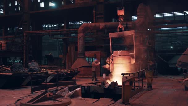 주물 작업장에서 빔 크레인으로 이동하는 용융된 액체 철이나 금속을 담은 사다리 용기. 강철 제조 공정, 중금속 산업 — 비디오