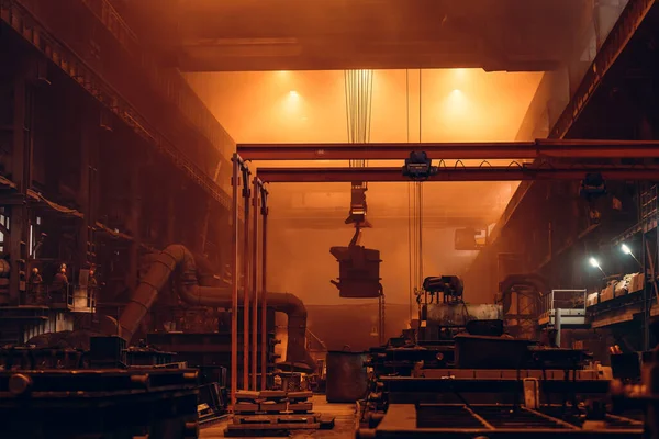 Stahlhüttenwerk oder Gießerei Innenraum mit großen Schöpfkelle Container mit geschmolzenem Eisen bewegt sich auf Trägerkran vom Hochofen zu Form, Schwerindustrie-Konzept — Stockfoto