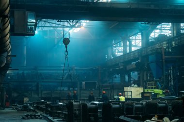 Büyük endüstriyel atölye veya çelik ürünleri ve işçilerin mavi renkli metal fabrikalarında çalıştığı depo.