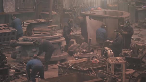 Grand atelier avec des ouvriers métallurgistes travaillant avec des pièces en fonte, traitement post-coulée à la fonderie de l'aciérie, sécurité au travail et travail d'équipe dans l'industrie métallurgique — Video