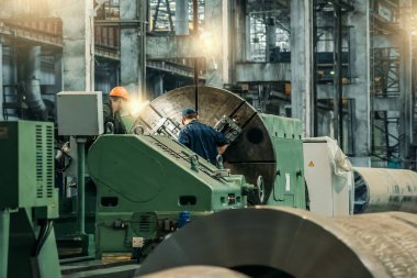 Fabrika işçileri atölyedeki otomatik makineleri tamir ediyor. Metal fabrikası ağır sanayi