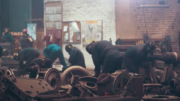 Atelier avec les ouvriers de l'usine métallurgique travaillent avec des pièces en fonte, traitement post-coulée à la fonderie de l'aciérie, industrie métallurgique — Video