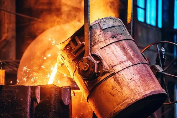 Molten metal pour from ladle Into sand mold. Iron casting process in metallurgy foundry plant, heavy industry