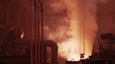 Geniş hangarda parlak duman ve patlama fırınından gelen ışıkla metalürji endüstrisi dökümhanesinin içinde.