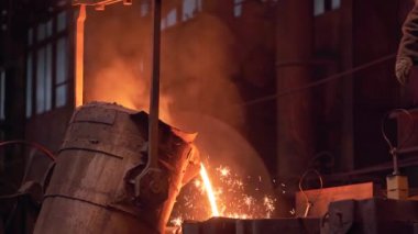 Metal döküm işlemi. Erimiş sıvı demir kepçe kabından küfe dökülüyor.