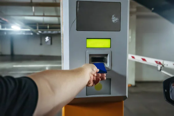 Man in car leaves underground parking in mall by paying with card near exit gate