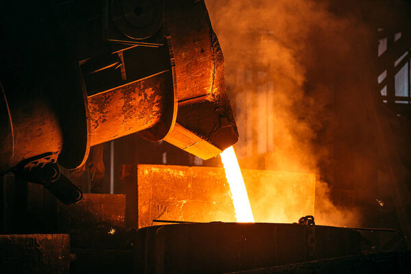 Foundry. Metal Cast Process. Molten Iron pouring with sparks and smoke in metallurgical plant.
