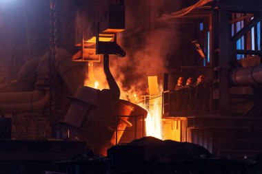 Sıvı demir, kepçeden dökülen erimiş metal, metalurji fabrikası, dökümhane kalıpları.