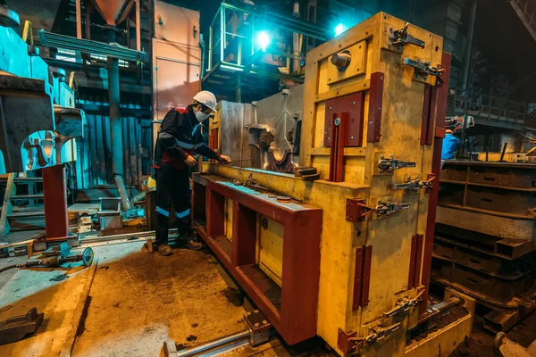 Unbekannter Arbeiter in Uniform, Helm und Schutzmaske arbeitet an Maschine in Hüttenwerk — Stockfoto