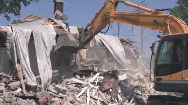 Kazı kovası yıkılan binanın çöplerini ve enkazlarını kırıyor. Evin yıkılması.