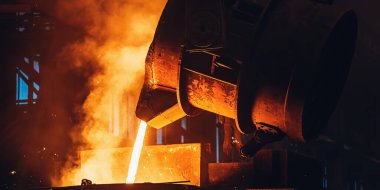 Erimiş metal büyük kepçeden dökülüyor. Demir döküm işlemi. Metalurjik bitki. Çelik fabrikası
