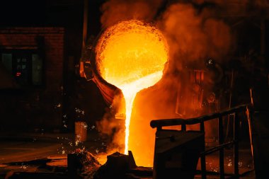 Dökümhane metalurji fabrikasındaki kepçeden dökülen sıvı metaller kalıba dökülüyor.