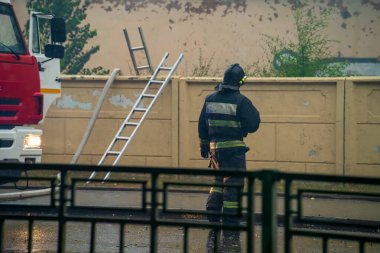 İtfaiyeciler olay yerinde yangın merdivenleri ve itfaiye arabalarıyla duvarda dikiz aynasıyla bekliyorlar.