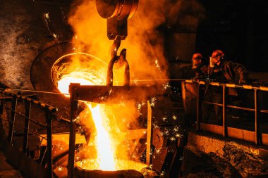 Demir dökme. Erimiş metal, patlama fırınından kepçeye dökülüyor. Dökümhane atölyesinde çelik üretimi. Metalurji fabrikası, ağır sanayi