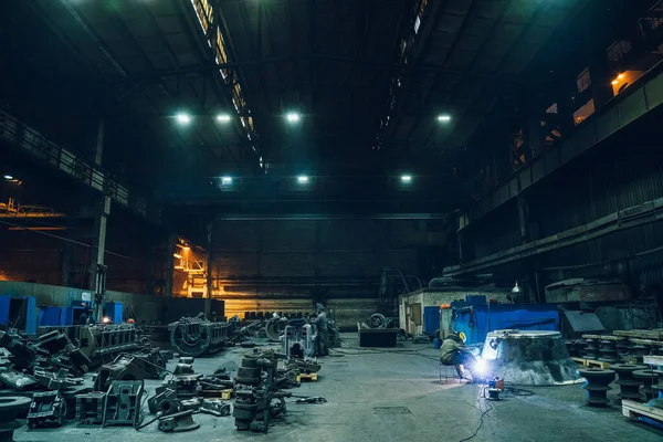 Metallurgische fabriek werkplaats interieur met werkende lasser en metalen producten klaar voor verwerking, zware industrie — Stockfoto