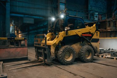 Metalurji atölyesinde küçük yükleme traktörü veya biçme makinesi çalışıyor