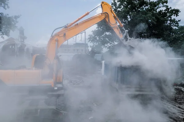 Penghancuran rumah tua oleh penggali dengan banyak debu. Ember ekskavator menghancurkan struktur beton — Stok Foto