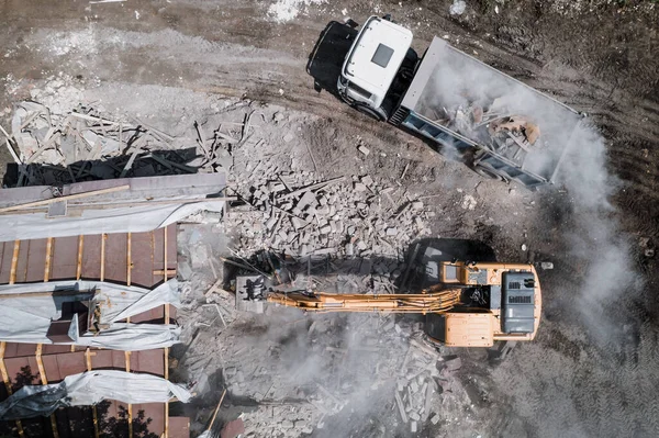 Sloop van het gebouw door industriële graafmachine. Emmer breekt muren en dak van oud huis vol stof, luchtfoto 's — Stockfoto