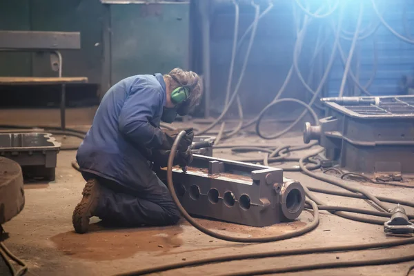 Unrecognizable worker processes cast iron product after smelting in metallurgical plant or foundry at workplace — Stock Photo, Image