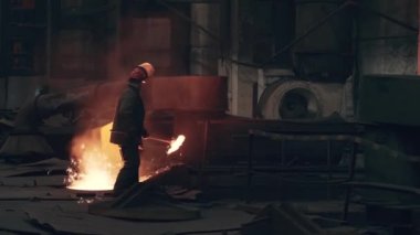 Metalurji fabrikasında erimiş metal ile çalışan tanınmayan bir işçi.