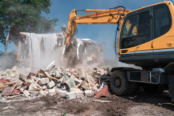Penghancuran rumah. Ekskavator kuning besar menghancurkan bangunan untuk konstruksi baru — Stok Foto